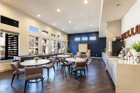 A well-lit dining area with a large table surrounded by chairs.