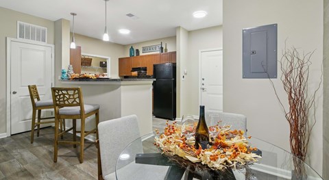 A kitchen with a table set for two and a bottle of wine.