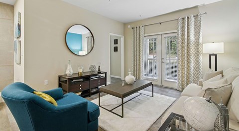 A blue armchair sits in a living room with a round mirror and a globe on the coffee table.