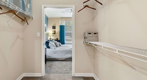 A bedroom with a bed and a closet with clothes hanging.