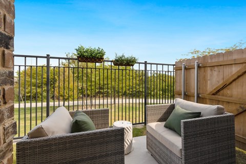 Two wicker chairs with cushions are placed on a patio.