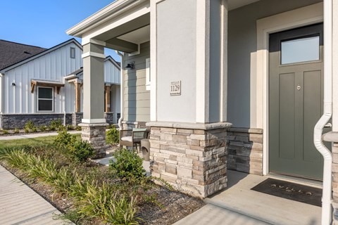 A house numbered with a color door and a stone pillar.