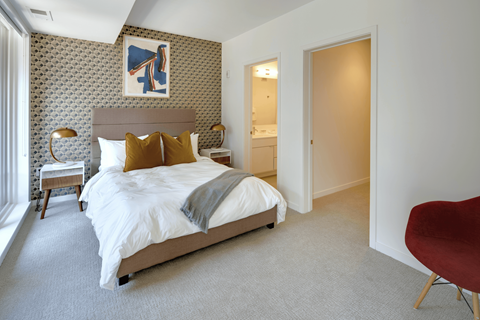 A bedroom with a large bed and a red chair.