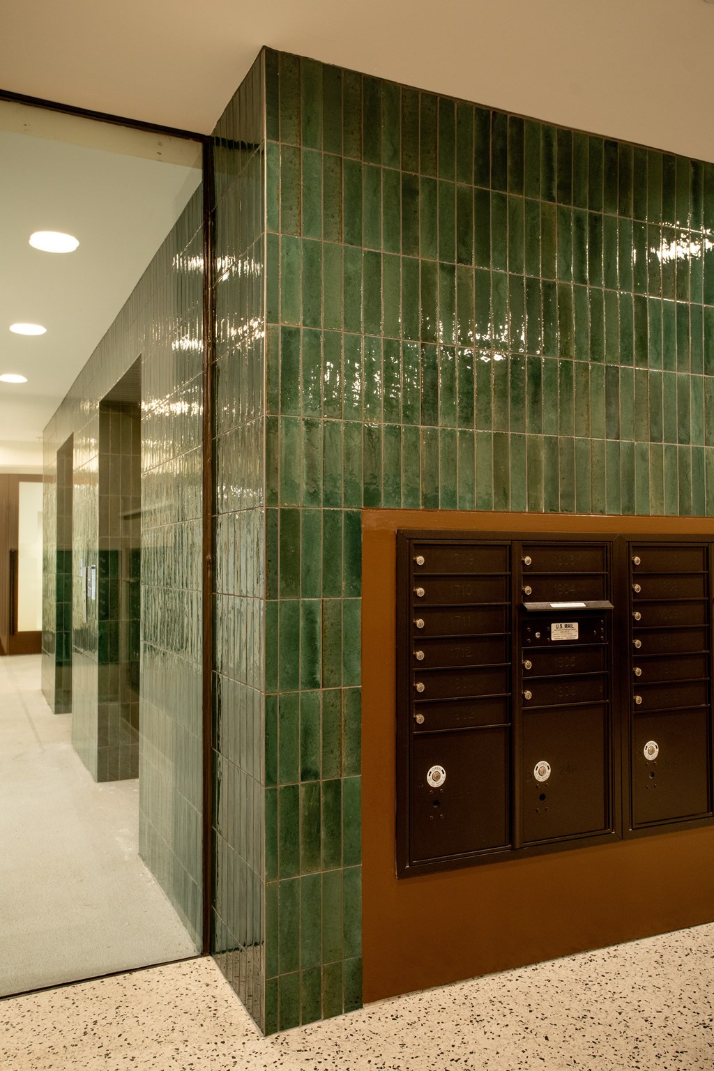 a large glass elevator lobby with green tile walls and a mail box