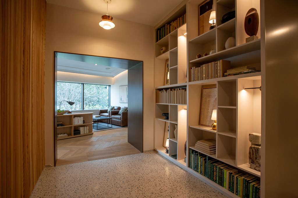 a hallway with a bookshelf and a door to a living room