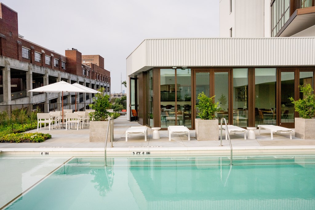 a swimming pool in front of a building with glass doors
