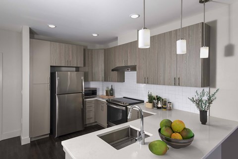 A modern kitchen with a stainless steel refrigerator and a bowl of fruit on the counter.