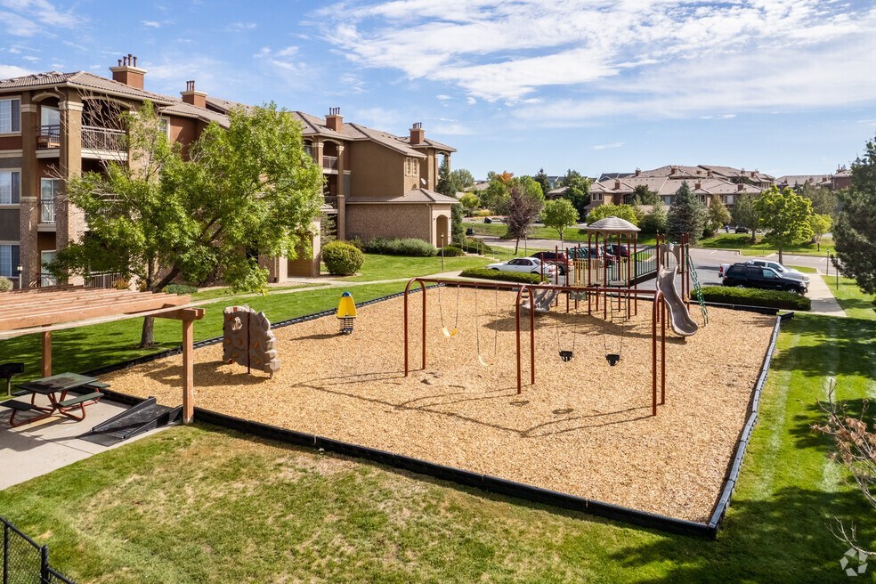 a playground in the middle of a park with houses in the background