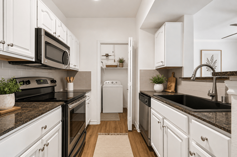 A modern kitchen with white cabinets and black countertops.