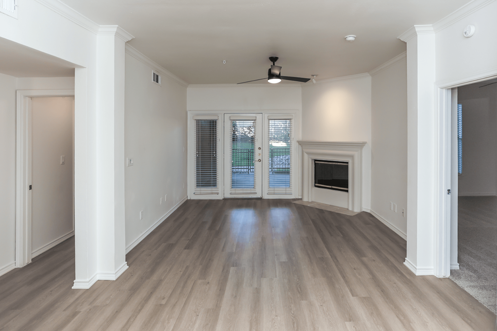 A spacious room with a ceiling fan and a fireplace.
