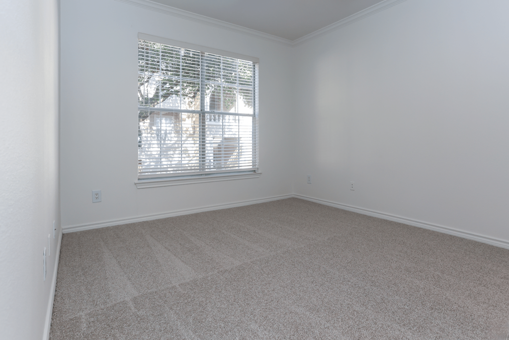 A room with a window covered by white blinds.