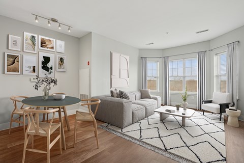 A living room with a grey couch, a round table with chairs, and pictures on the wall.