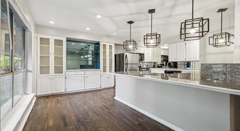 A kitchen with white cabinets and a wooden floor.