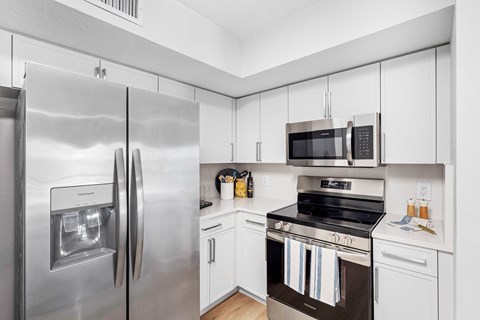 A modern kitchen with a stainless steel refrigerator and white cabinets.