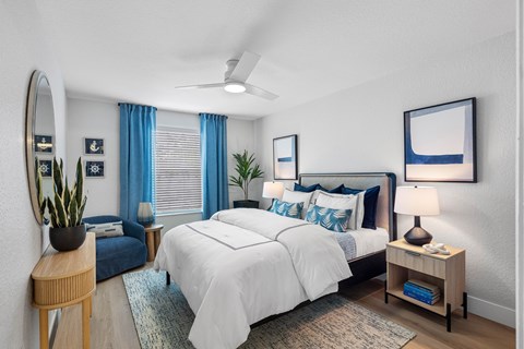 A bedroom with a large bed, a side table with a lamp, and a mirror on the wall.