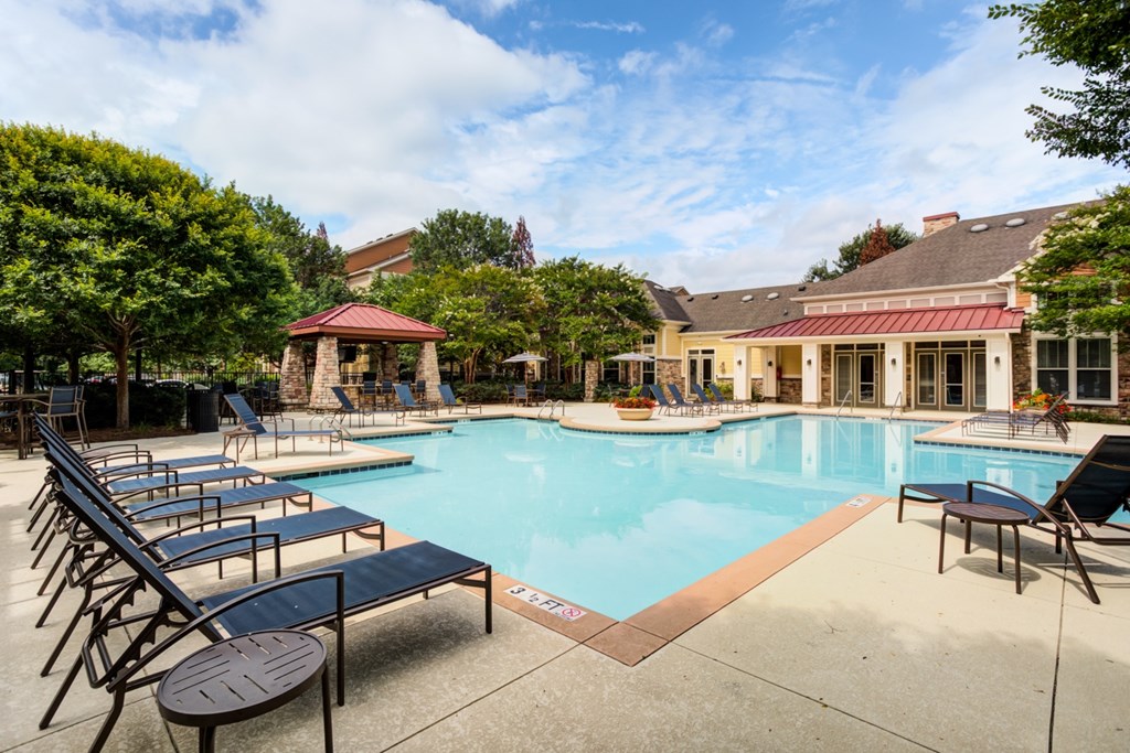 1, 2, and 3-Bedroom Apartments In Hendersonville, TN - The Grove At Waterford Crossing - Resort-Style Pool With Lounge Chairs, And Surrounded By Clubhouse And Trees.