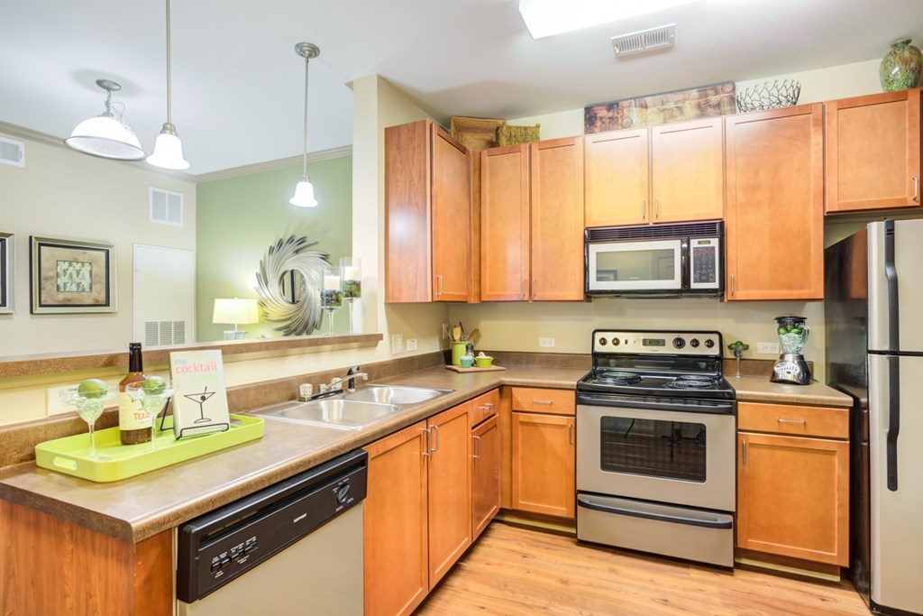 Apartments In Hendersonville For Rent - The Grove At Waterford Crossing - Kitchen With Brown Cabinets, Long Counters, And Appliances.