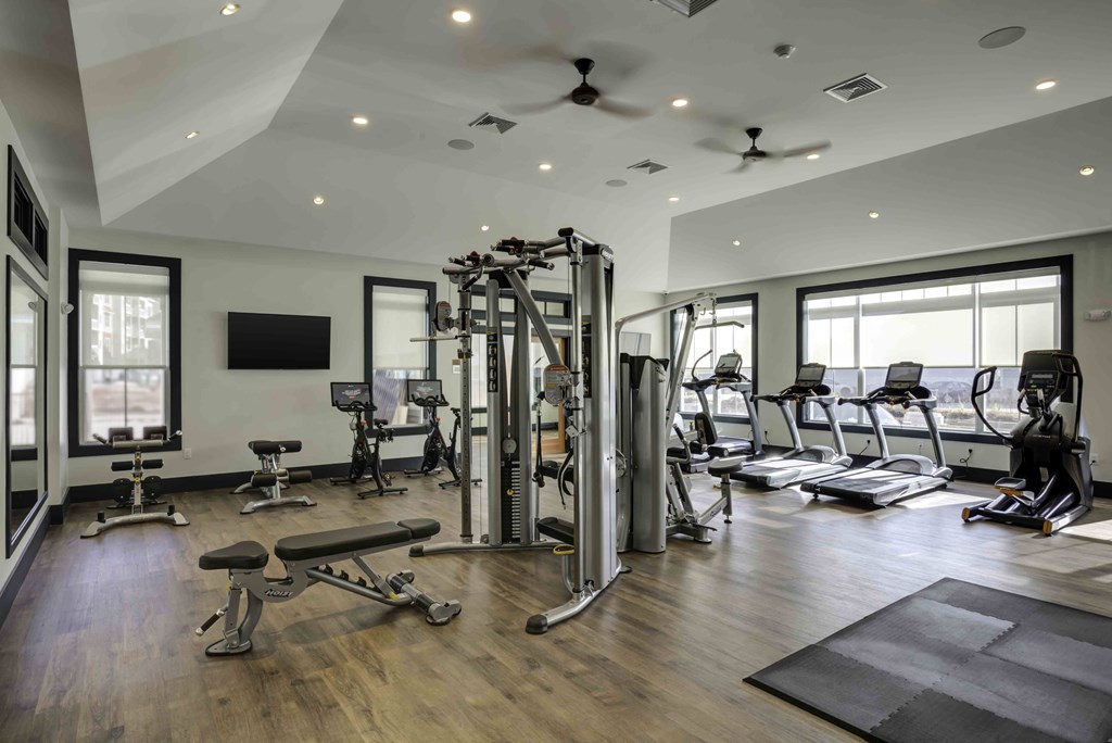 A spacious gym with a variety of equipment and a flat screen TV mounted on the wall.