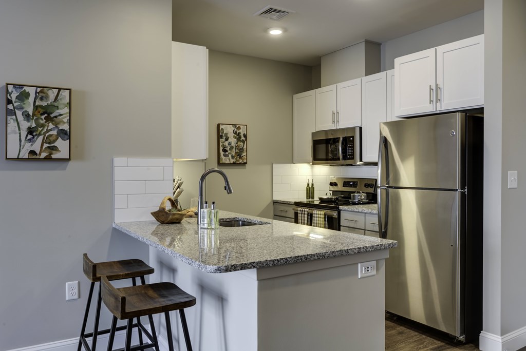 A kitchen with a granite countertop and stainless steel appliances.