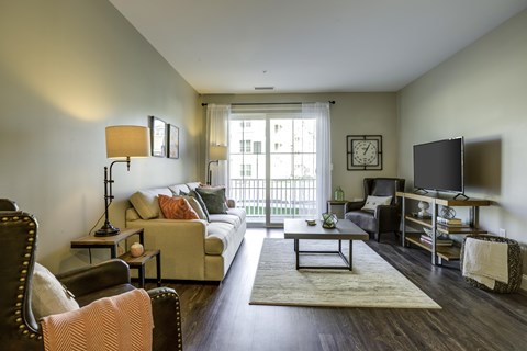 A living room with a couch, chair, and a table with a lamp on it.