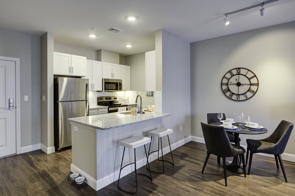 A modern kitchen with a bar area and a dining table set for four.