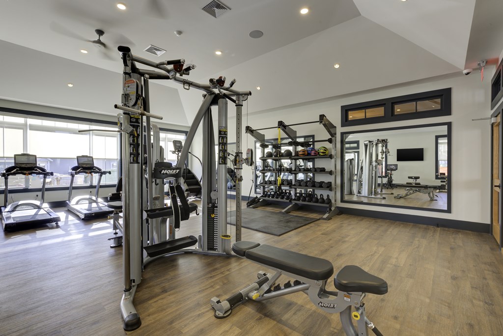 A gym with a variety of equipment including a weight bench, a squat rack, and a mirror.