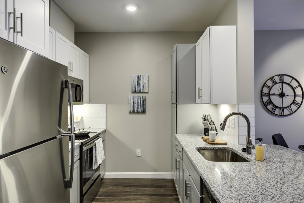 A modern kitchen with a granite countertop and stainless steel appliances.
