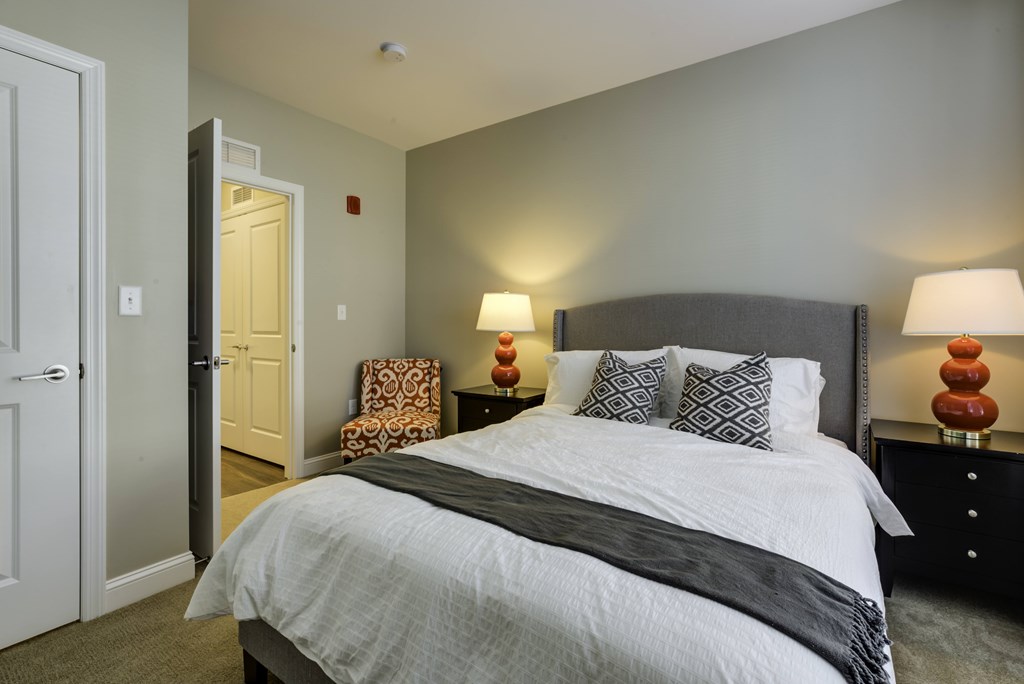 A bedroom with a large bed and two lamps.