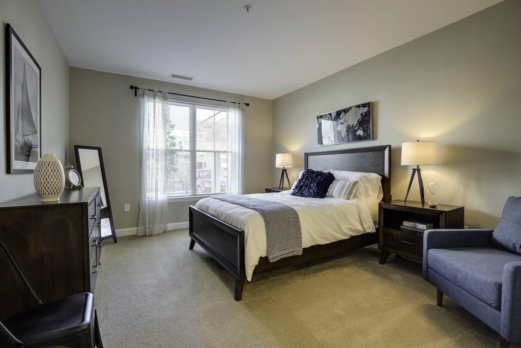 A bedroom with a large bed and a chair.