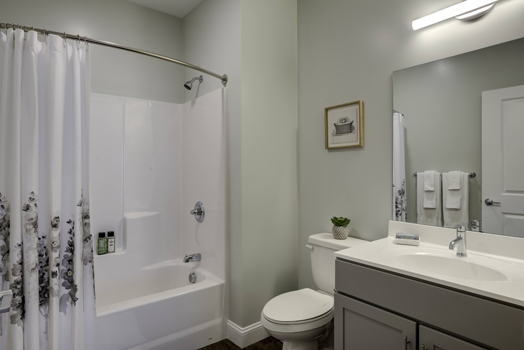 A white bathroom with a toilet, sink, and shower.