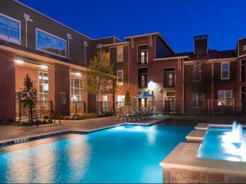 A swimming pool in front of a building at night.