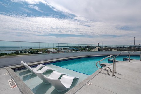 a swimming pool on the roof of a building with two chairs