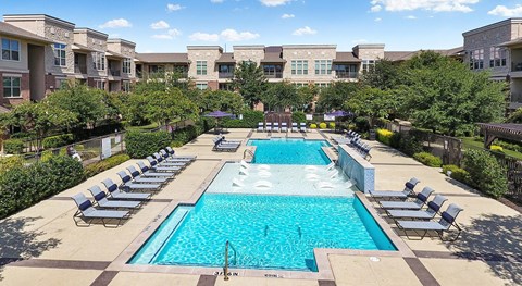 A large swimming pool surrounded by lounge chairs and trees.