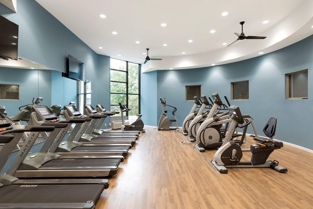 a gym with cardio equipment and weights on a wood floor