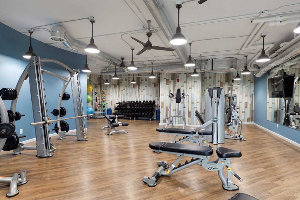a gym with weights and other exercise equipment on a wooden floor