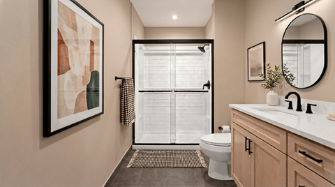 A bathroom with a toilet, sink, and a painting on the wall.