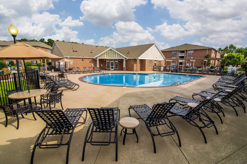 A pool surrounded by chairs and tables.