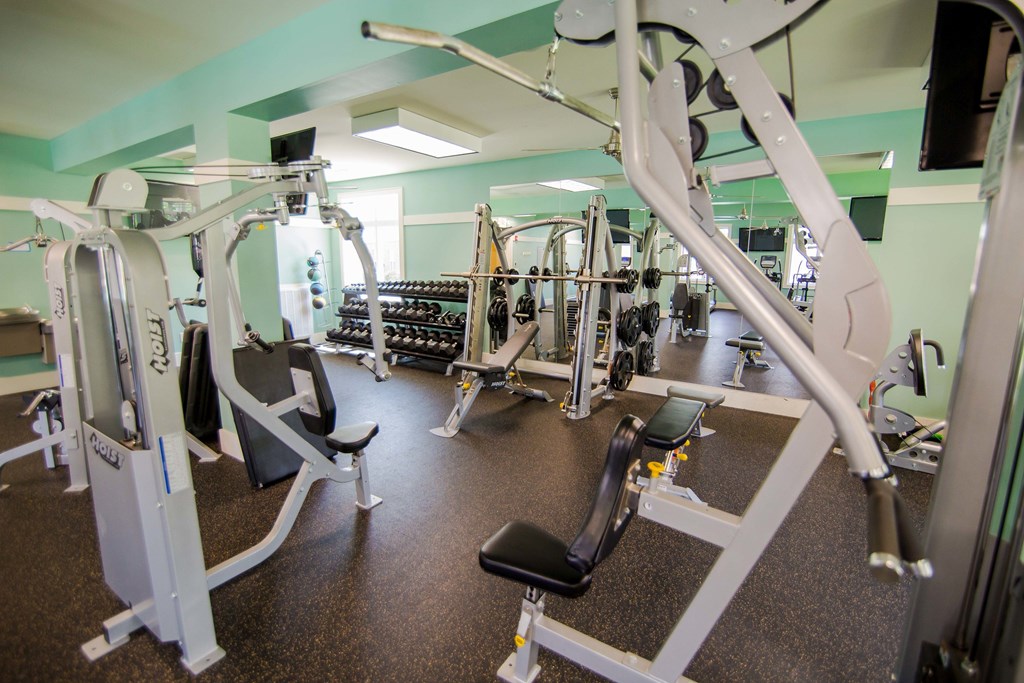 A gym with a variety of equipment including treadmills, weights, and exercise machines.