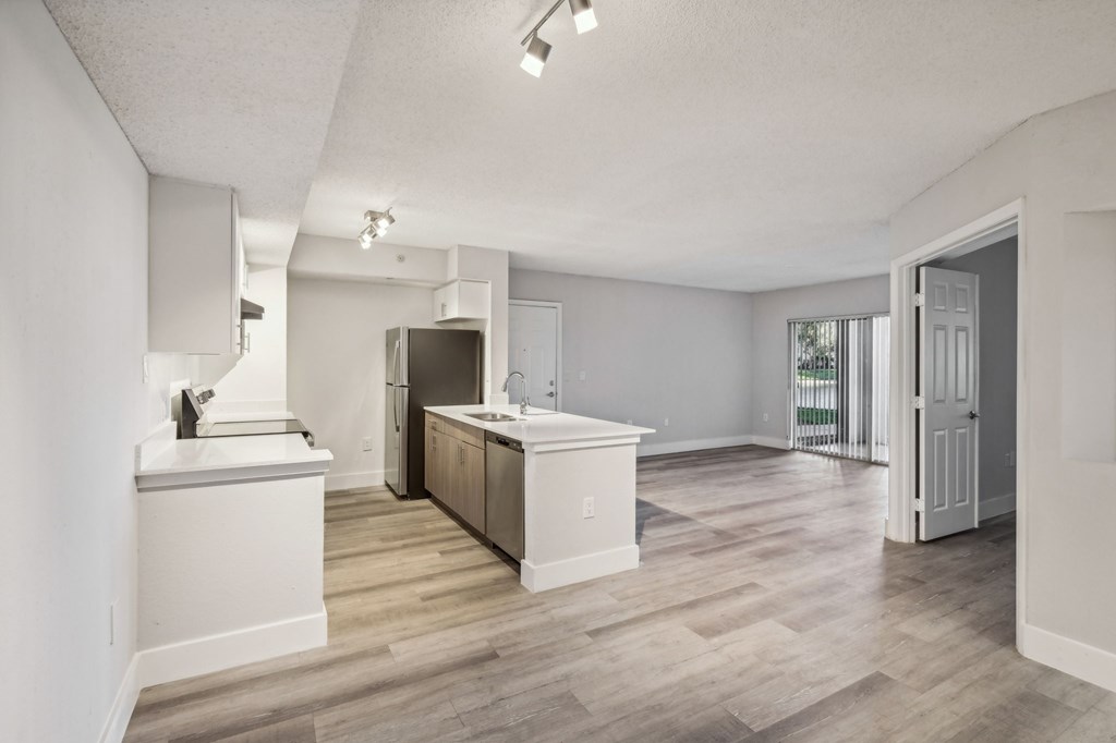 A kitchen with white cabinets and a wooden floor.