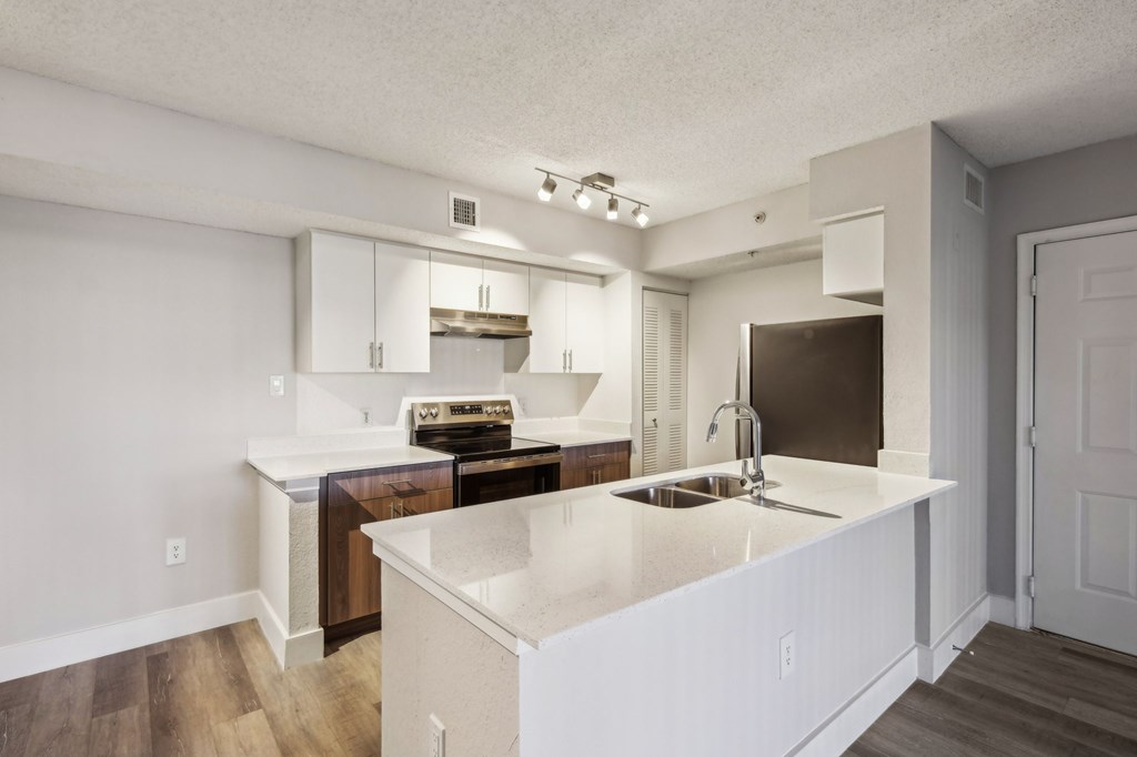 A kitchen with white countertops and wooden floors.