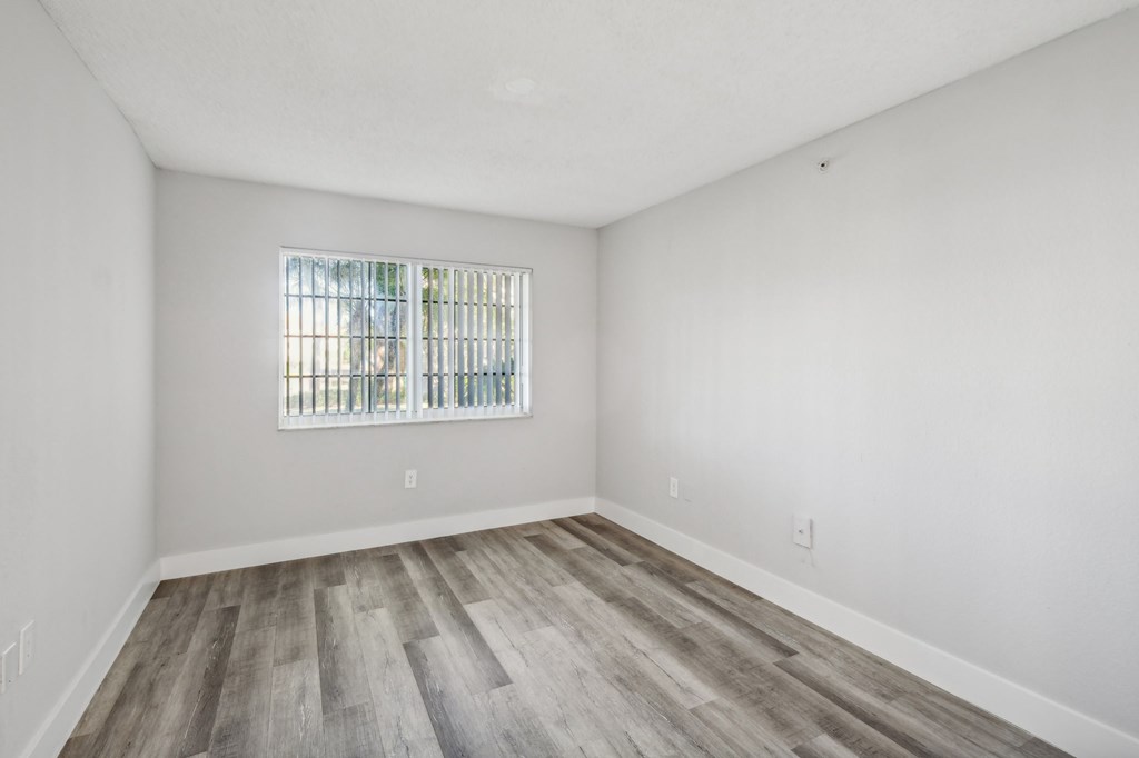 A room with a window and wooden flooring.