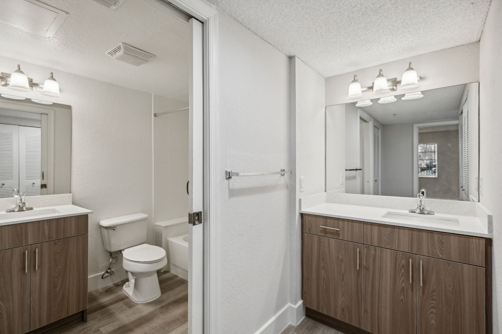 A white bathroom with a toilet, sink, and mirror.