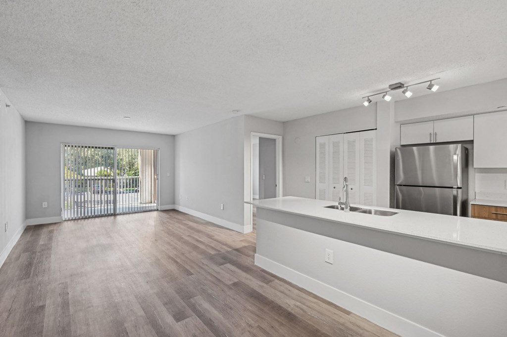 A kitchen with a refrigerator, sink, and wooden floors.