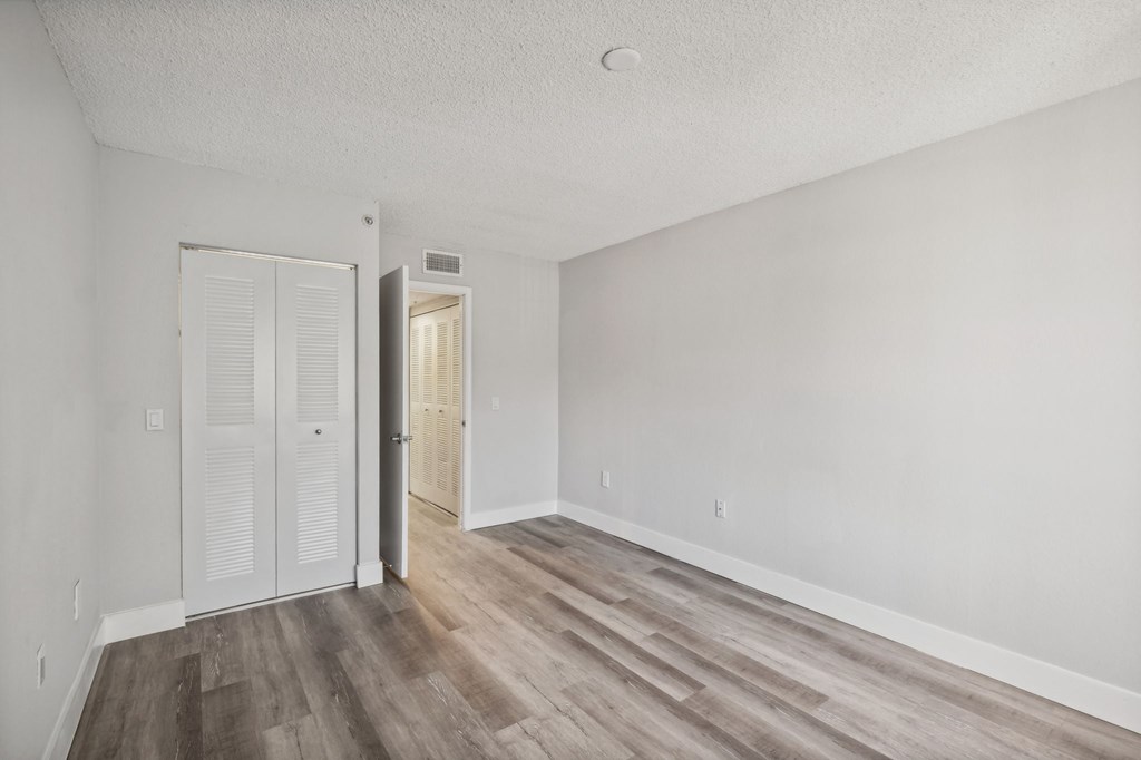A room with a white door and a wooden floor.
