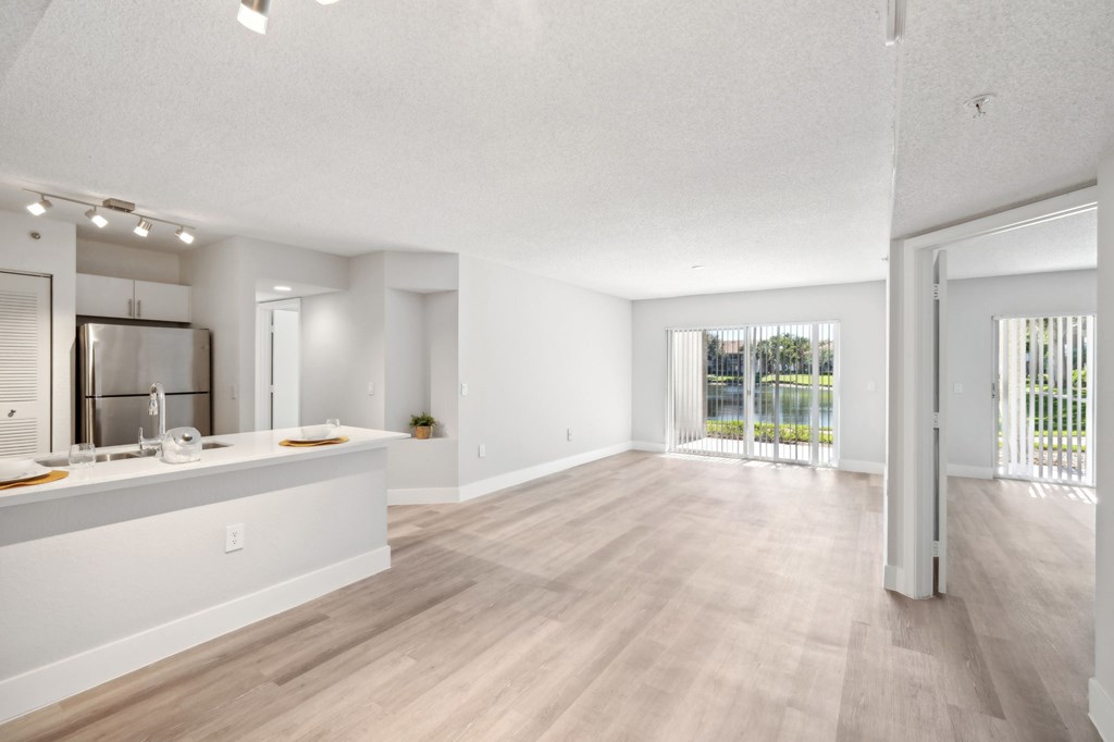 A spacious kitchen with white cabinets and a wooden floor.