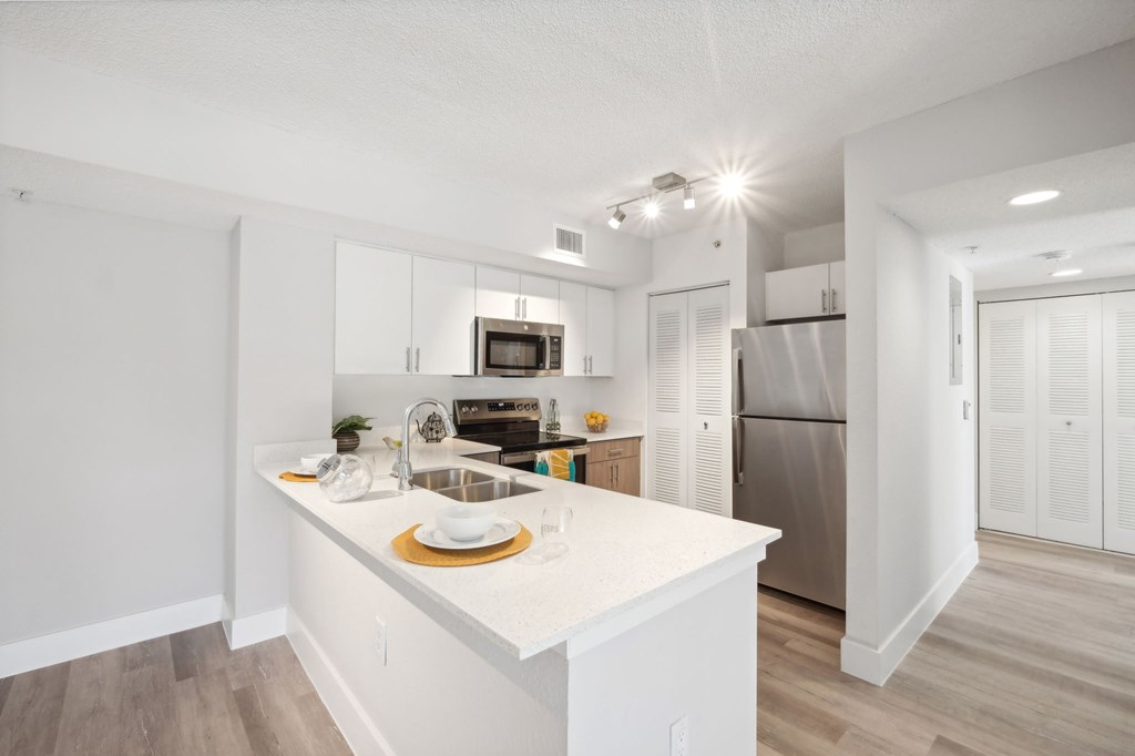 A kitchen with white cabinets and a white island.