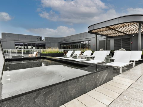 a pool with white lounge chairs in front of a building