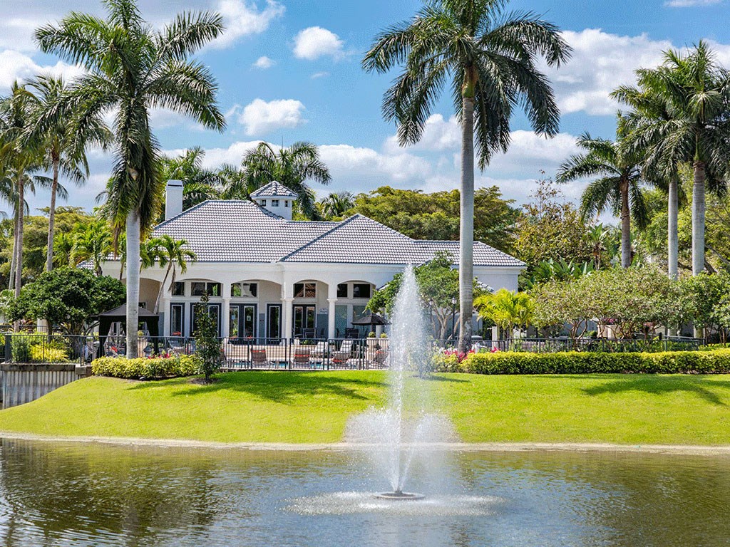 a fountain in front of a house with palm trees