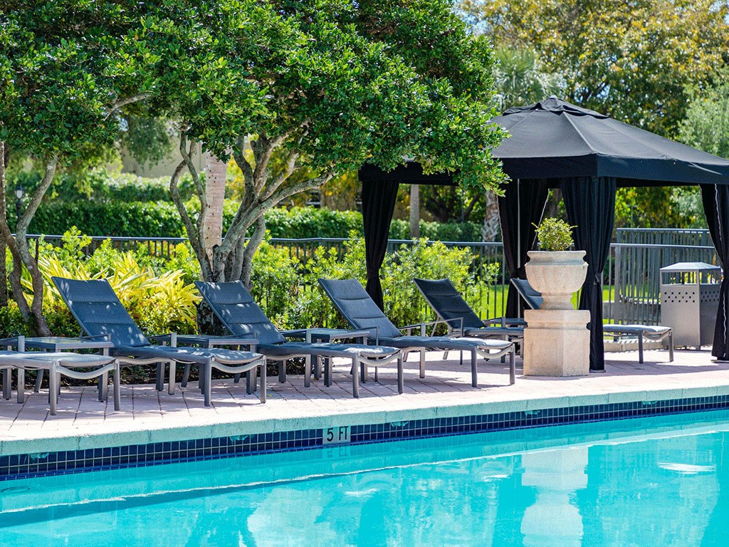 a swimming pool with blue chairs and a black gazebo