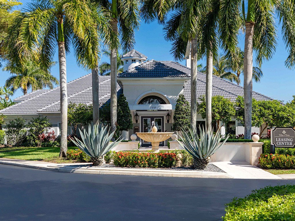 a fountain in front of a house with palm trees